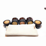 Five sample candles lined up along a calico bag