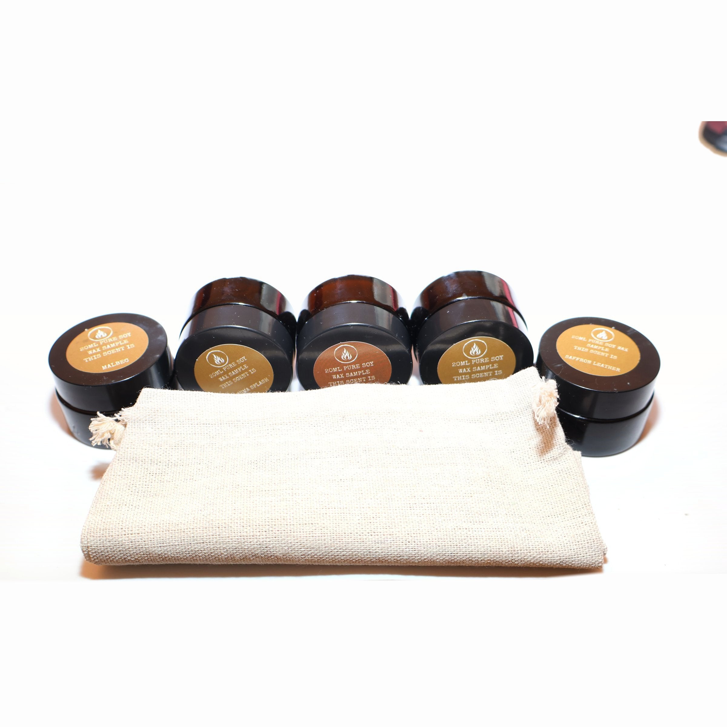 Five sample candles lined up along a calico bag